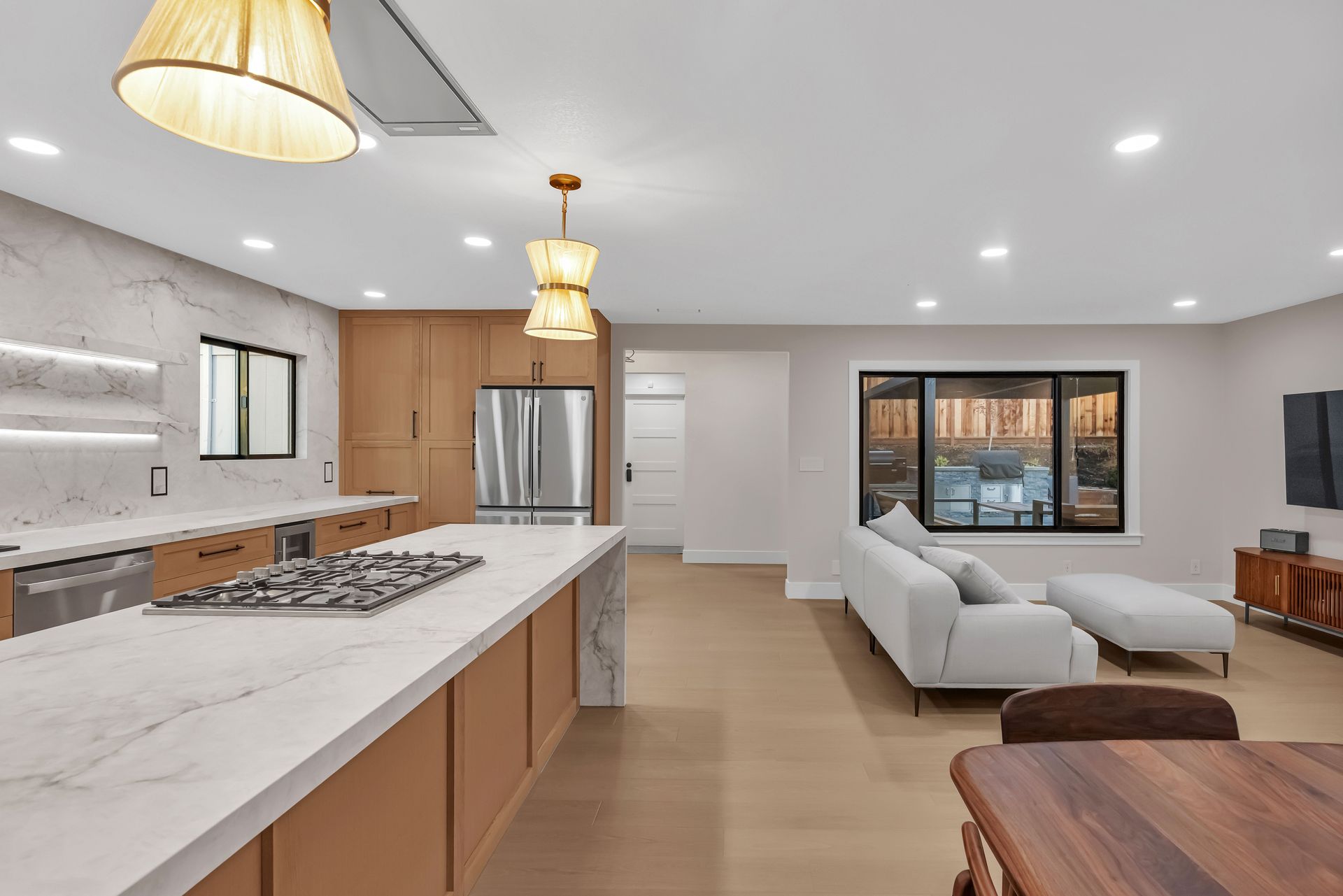 Open-concept kitchen and living area with olive green cabinets, stainless steel appliances, and a gray sofa.