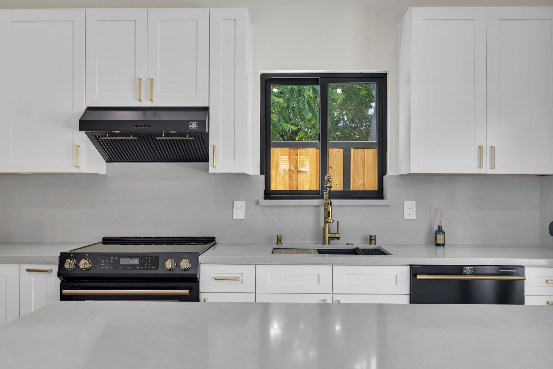 Modern kitchen with white cabinets, black appliances, and a window.