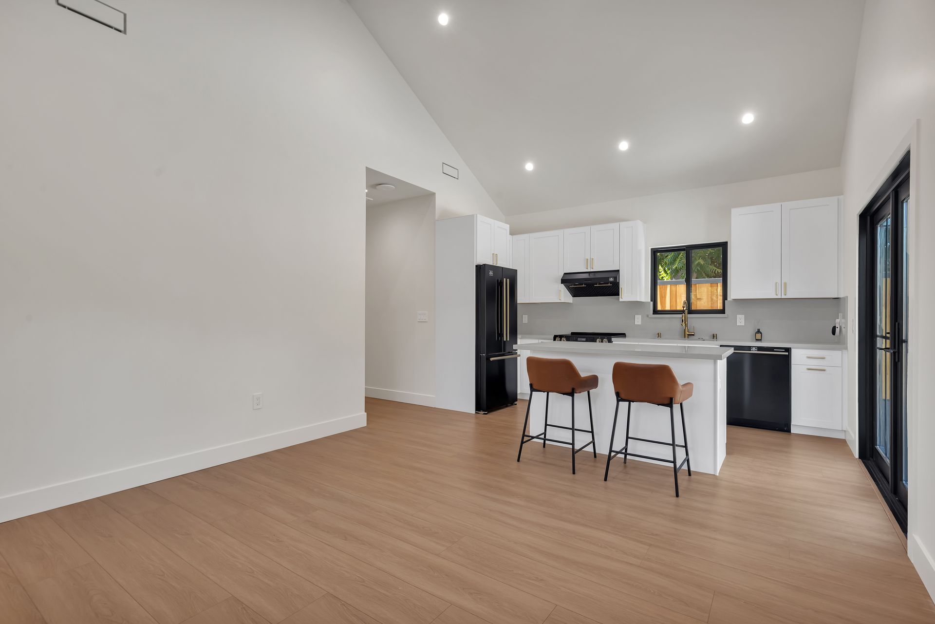Modern kitchen with white cabinets, island with stools, and dark appliances.