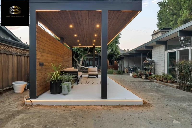 Modern kitchen with light wood cabinetry, white countertops, and two windows.