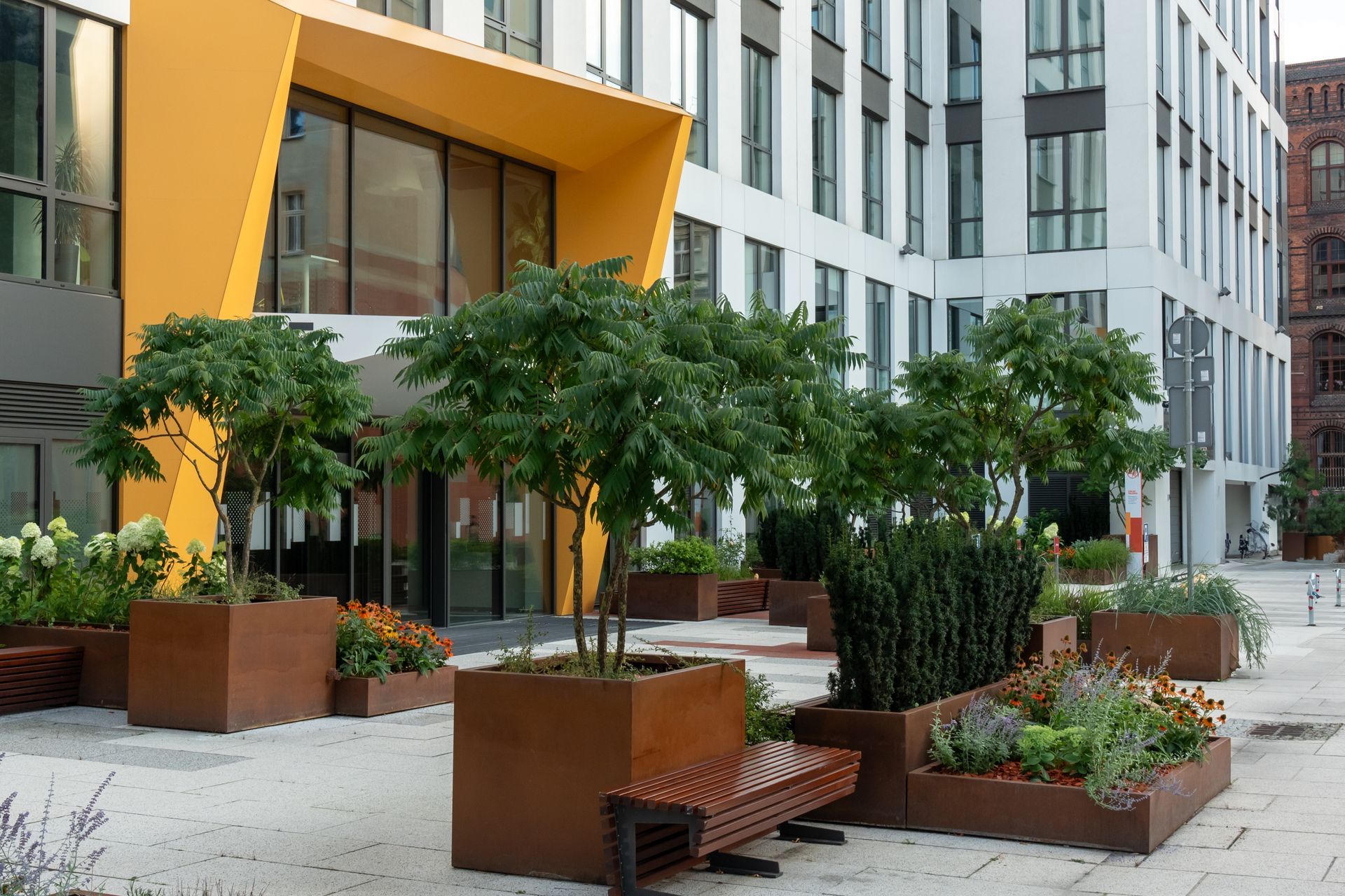 Modern home entryway with black door, console table, and light wood flooring. Kitchen visible in the background.