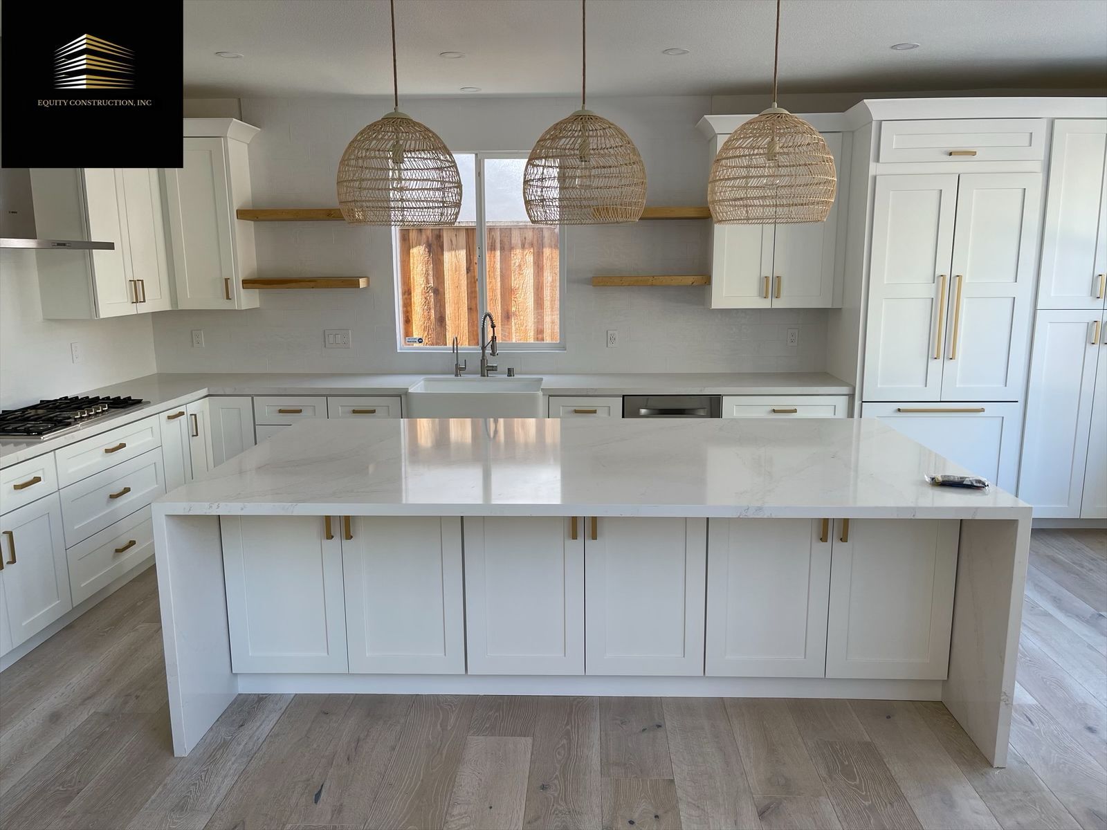 Modern kitchen with marble countertops, wood cabinets, stainless steel appliances, and pendant lighting.