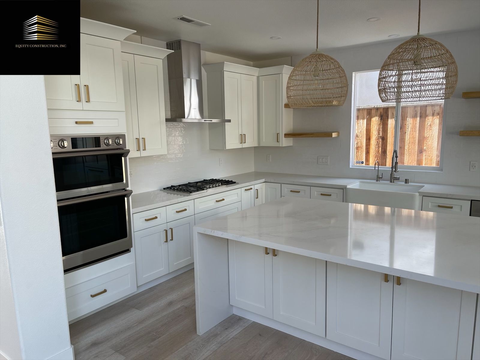 White kitchen with island, cabinets, oven, range, and woven light fixtures.