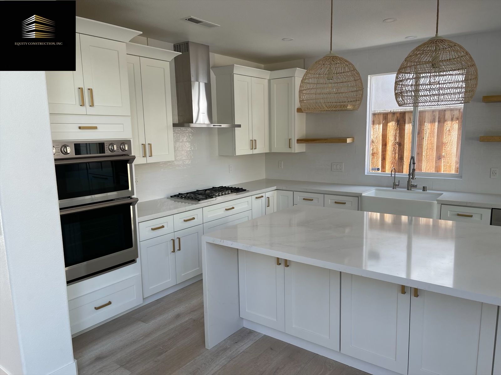 White kitchen with island, cabinets, double oven, and pendant lights.