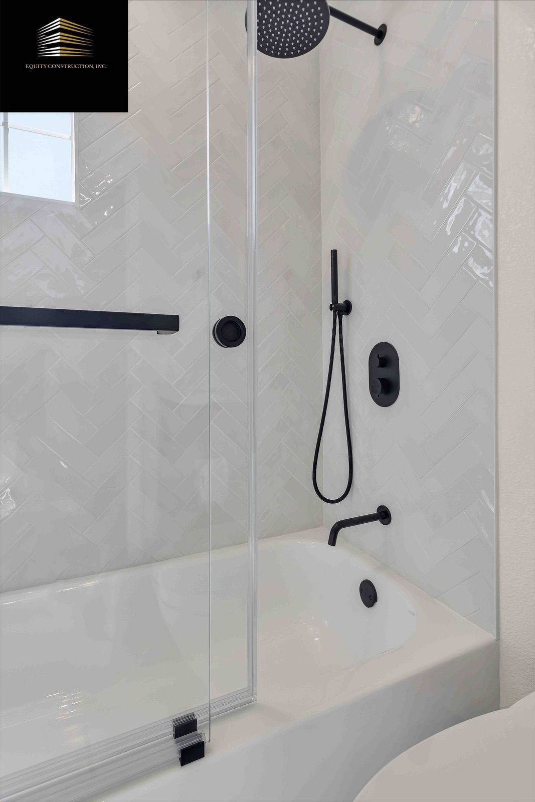 White bathtub with black fixtures, shower head, and glass door.