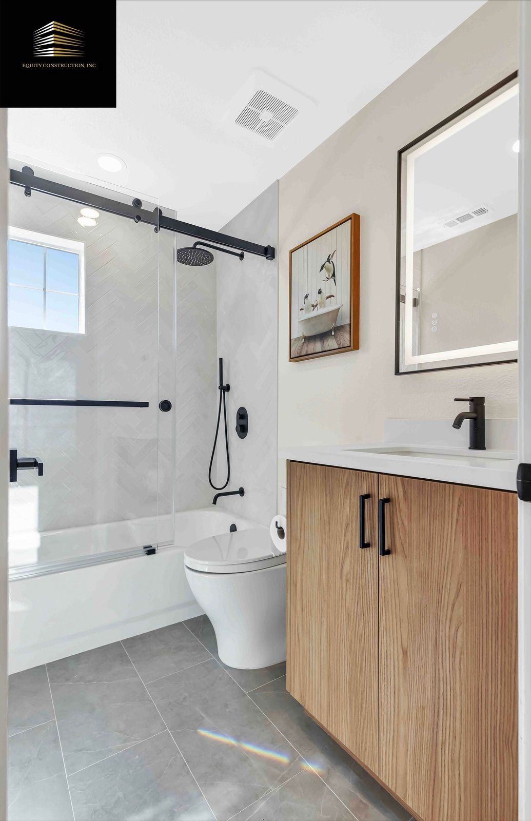 Modern bathroom with white and wood accents; shower, toilet, vanity, artwork.
