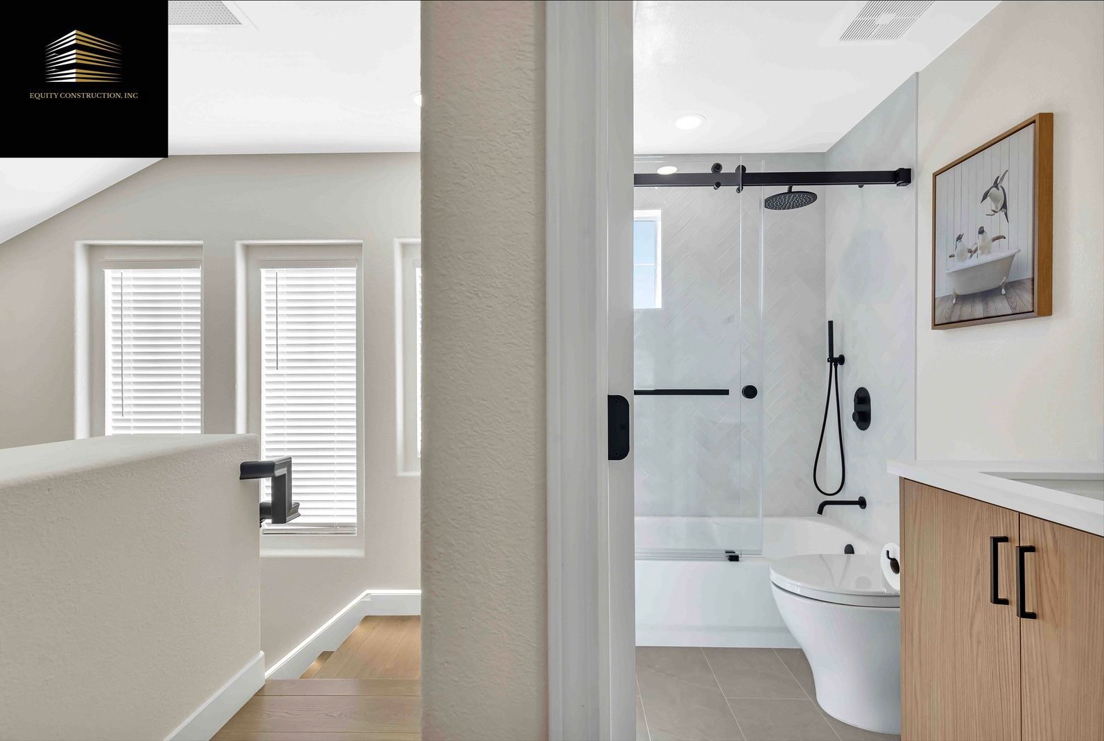 Bathroom with a modern shower, toilet, and vanity visible through an open door. Light colors and minimalist decor.