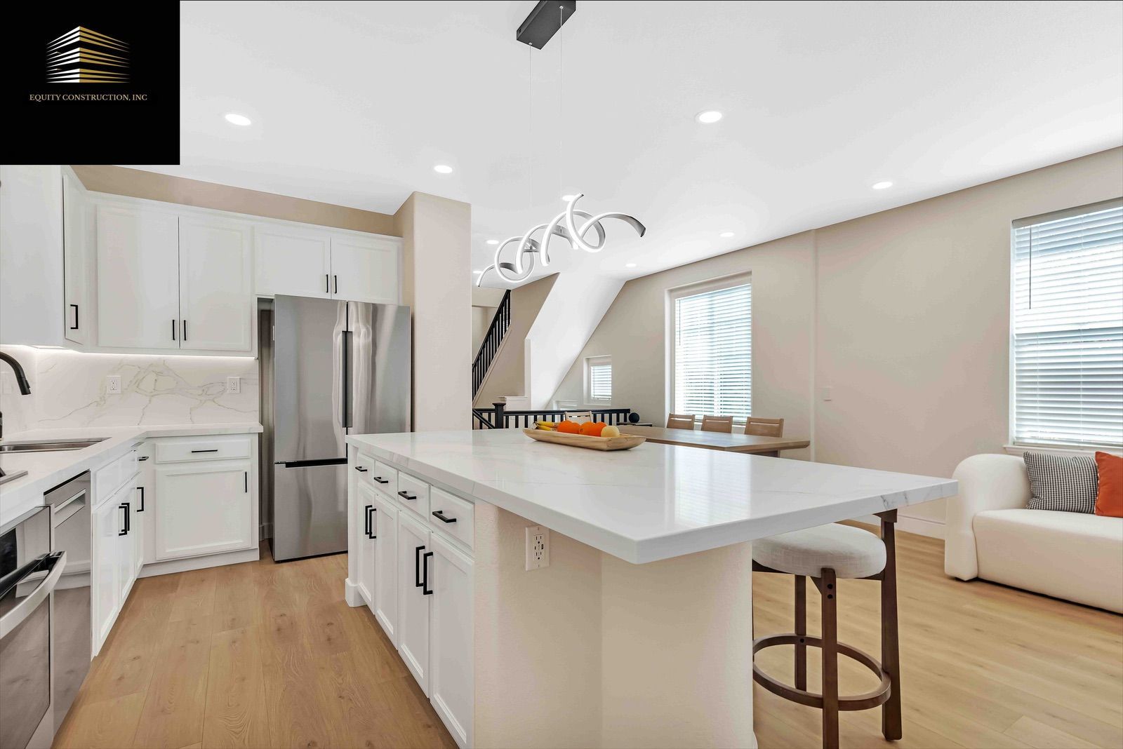 Modern kitchen with white cabinets, stainless steel appliances, island, and dining area.