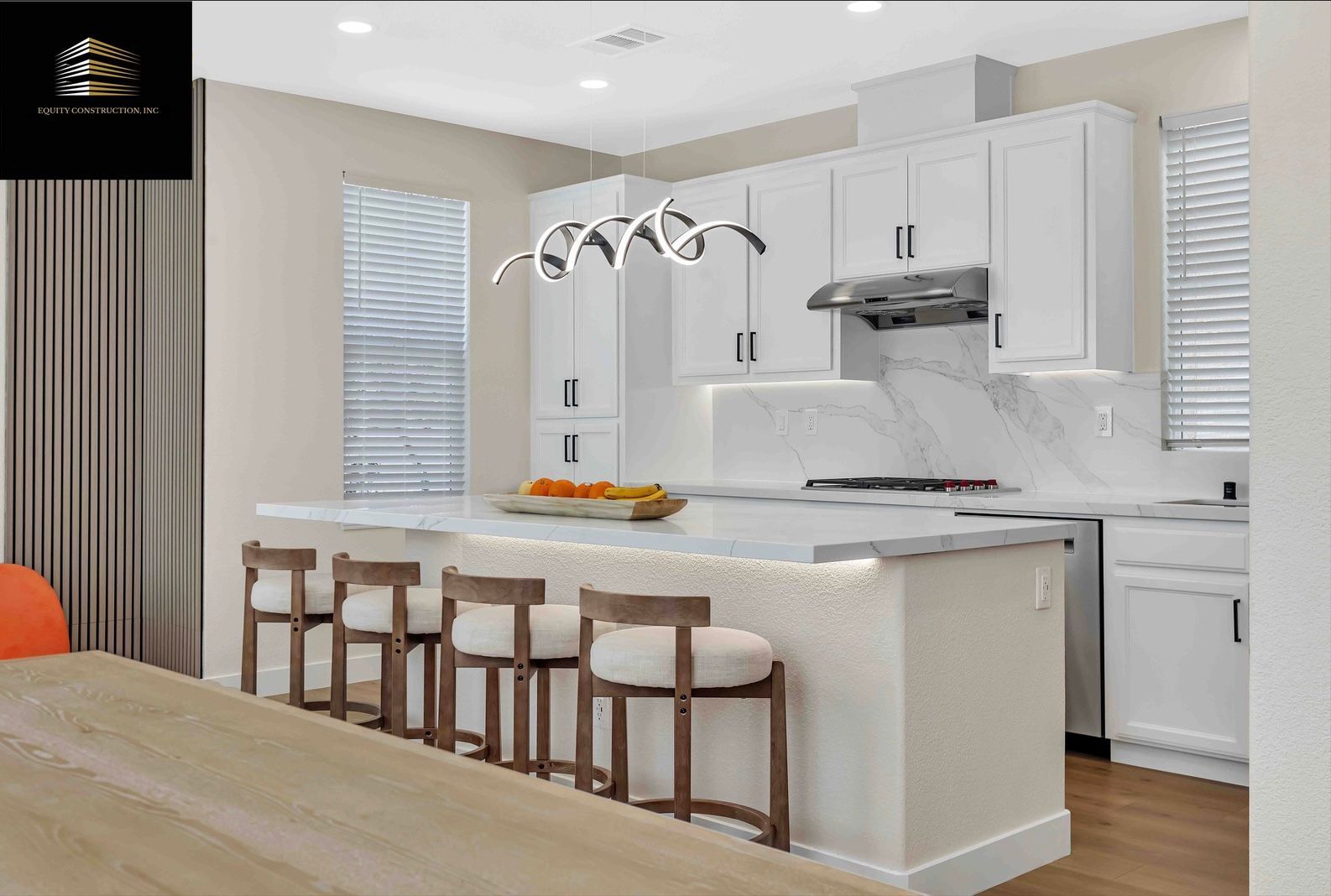 Modern kitchen with white cabinets, island, countertops, and wood bar stools; a chandelier hangs overhead.