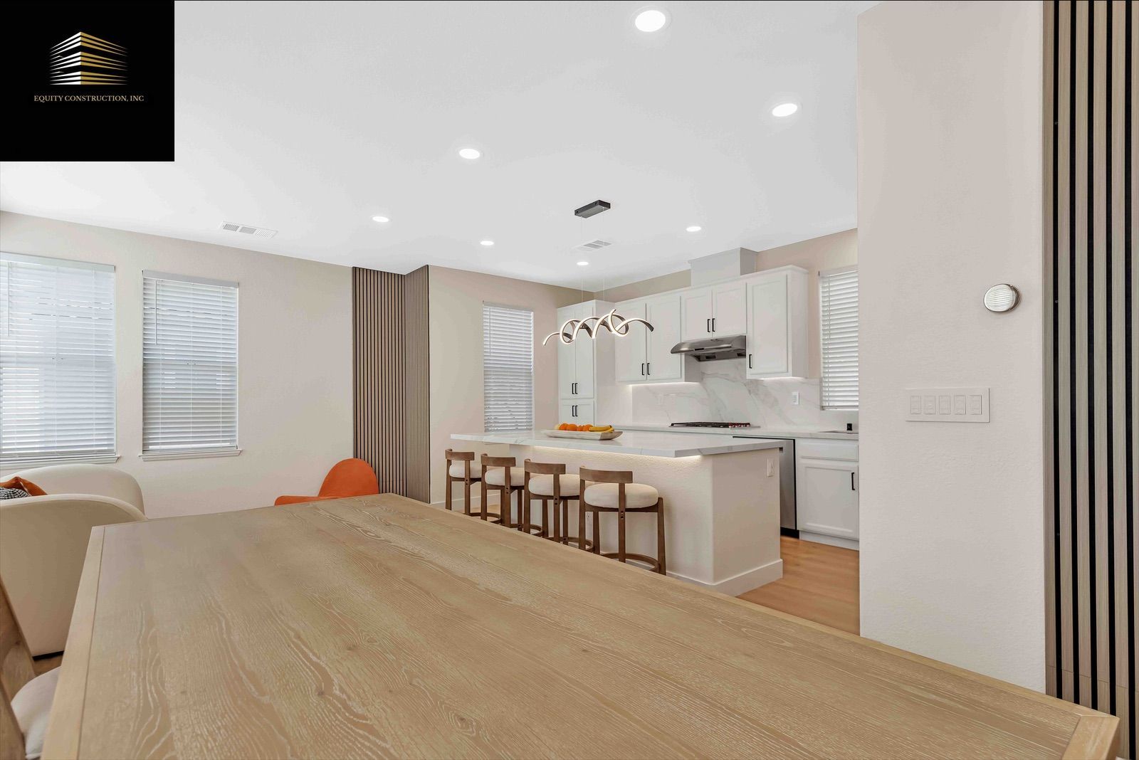 Modern open-concept kitchen and dining area with white cabinets, wood island, and large wood table.