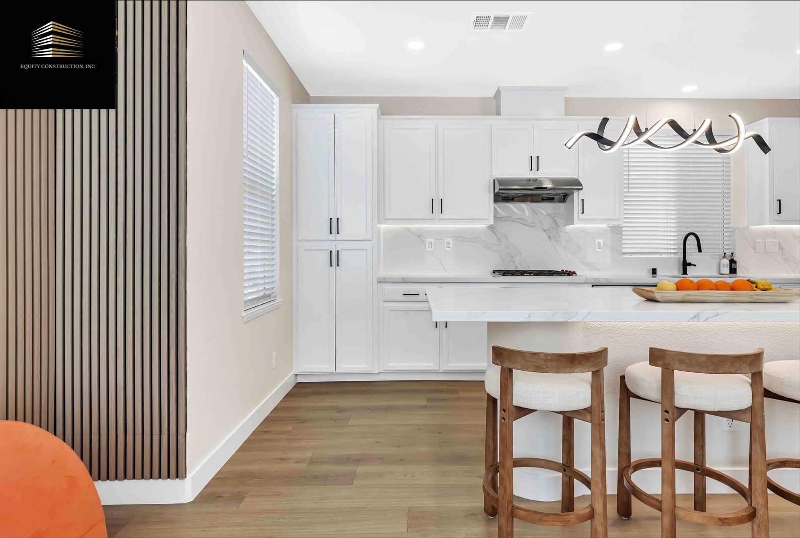 Modern kitchen with white cabinets, marble backsplash, and wooden island with bar stools.