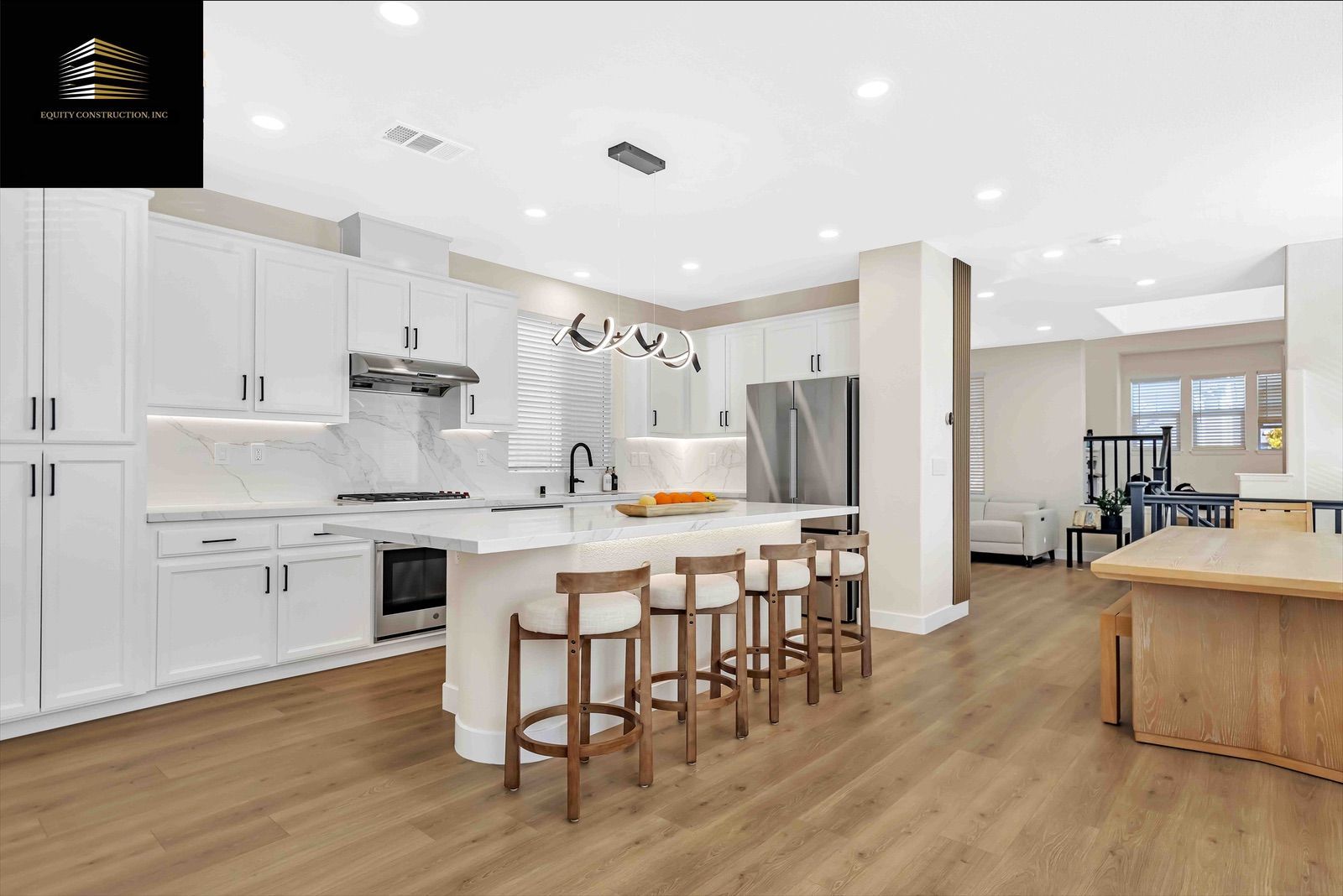 Modern kitchen with white cabinets, island with stools, and stainless steel appliances.