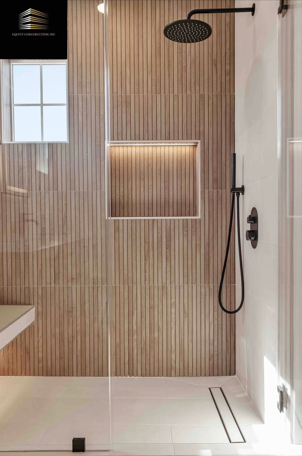 Modern shower with wood-look tile, glass door, black fixtures, built-in shelf, and small window.