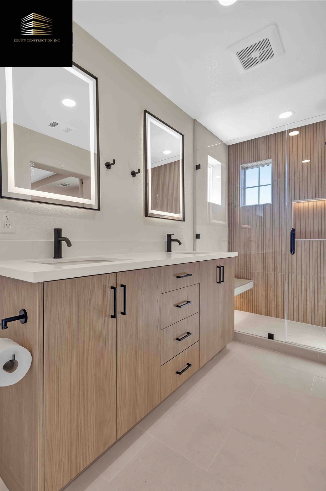 Modern bathroom with wood vanity, backlit mirrors, glass shower, and beige tile.