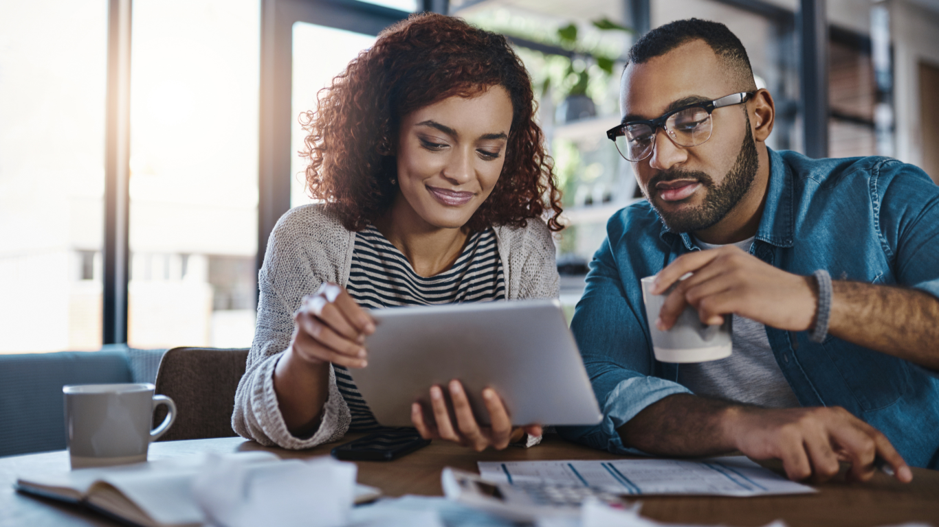 a man and a woman are looking at a tablet together