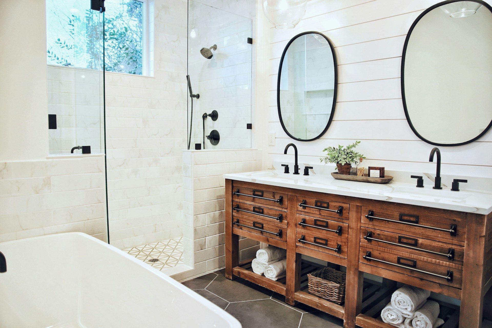 A bathroom with two sinks , two mirrors and a bathtub.