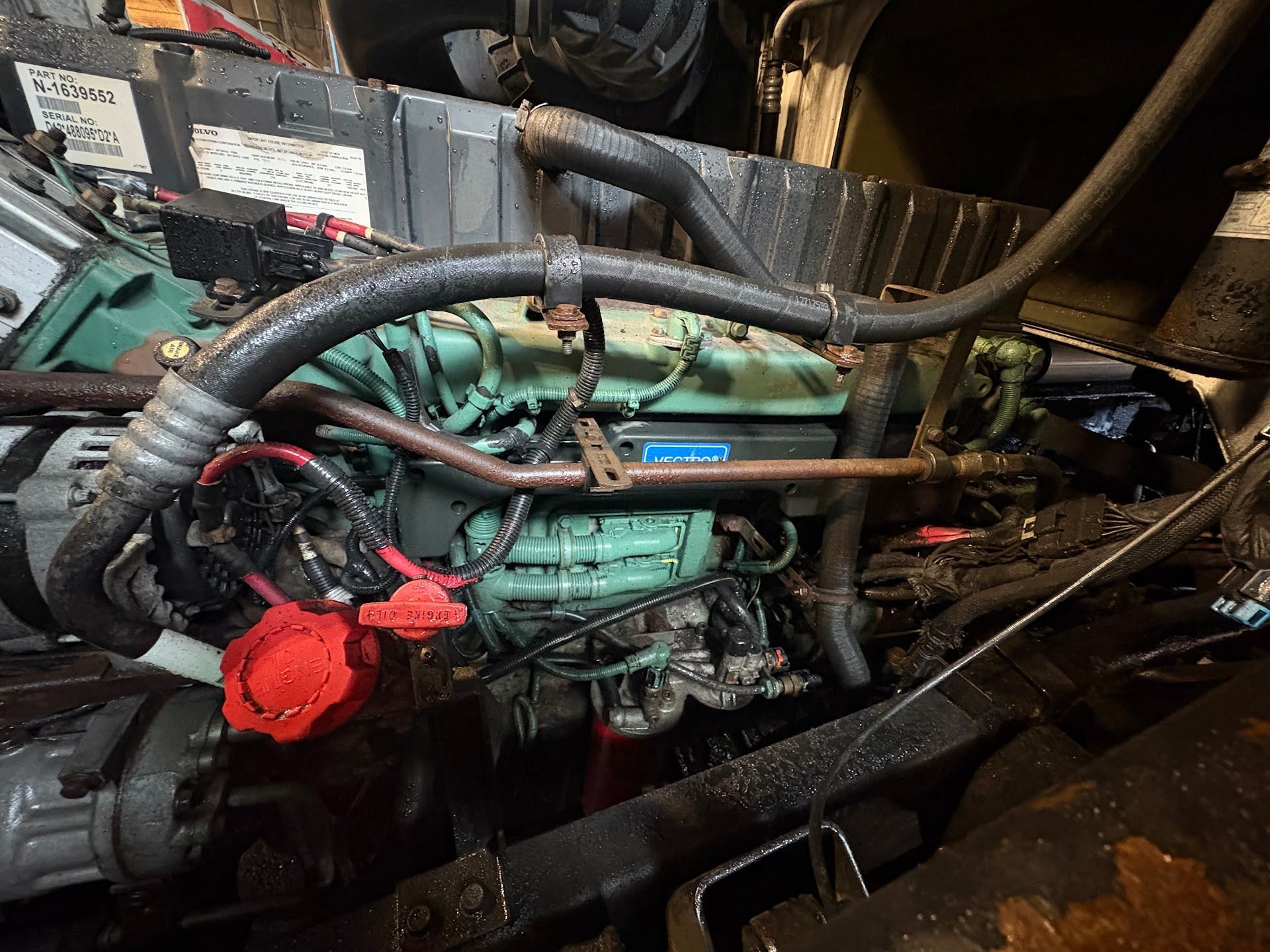 Green engine in an engine compartment, black hoses and wires, red cap visible. | Mega City Auto Niagara