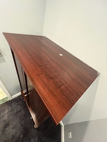Wooden cabinet with a dark, shiny surface against white and gray walls.