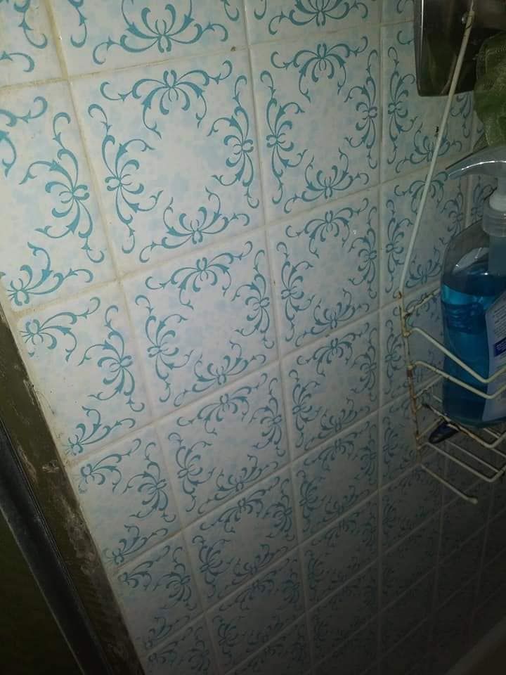 A shower stall with blue and white tiles and a soap dispenser.