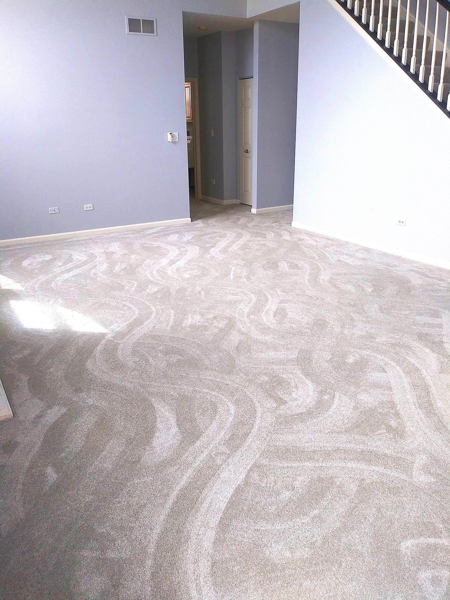 An empty living room with a staircase and a carpeted floor.
