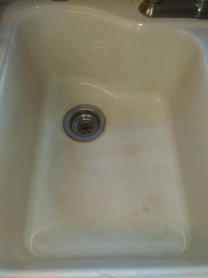A white kitchen sink with a drain in it.