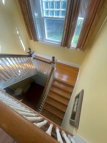Staircase, top-down view, wooden steps, white railing, yellow walls, window, natural light.