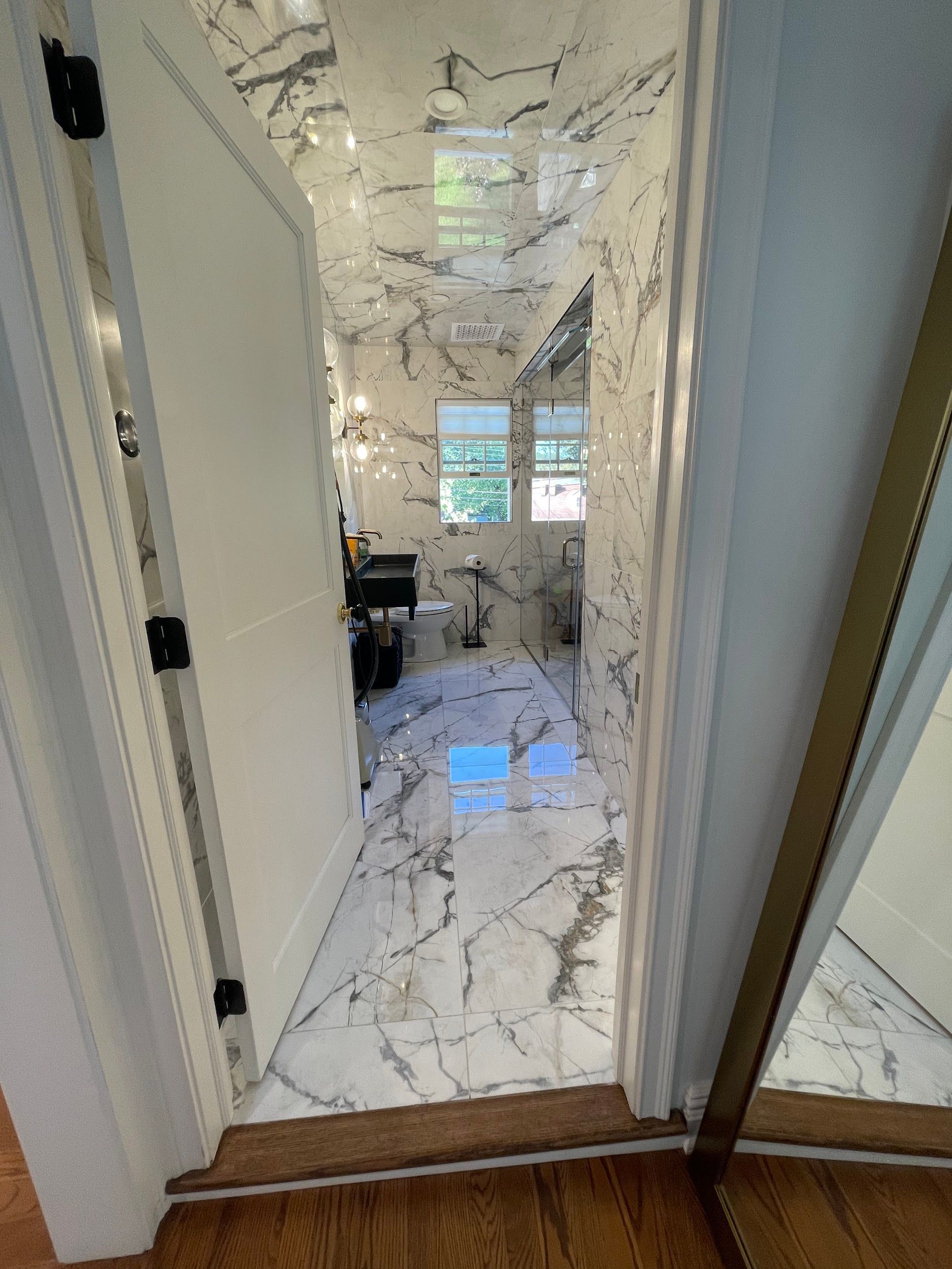 A doorway leading to a bathroom with marble floors and a mirror.