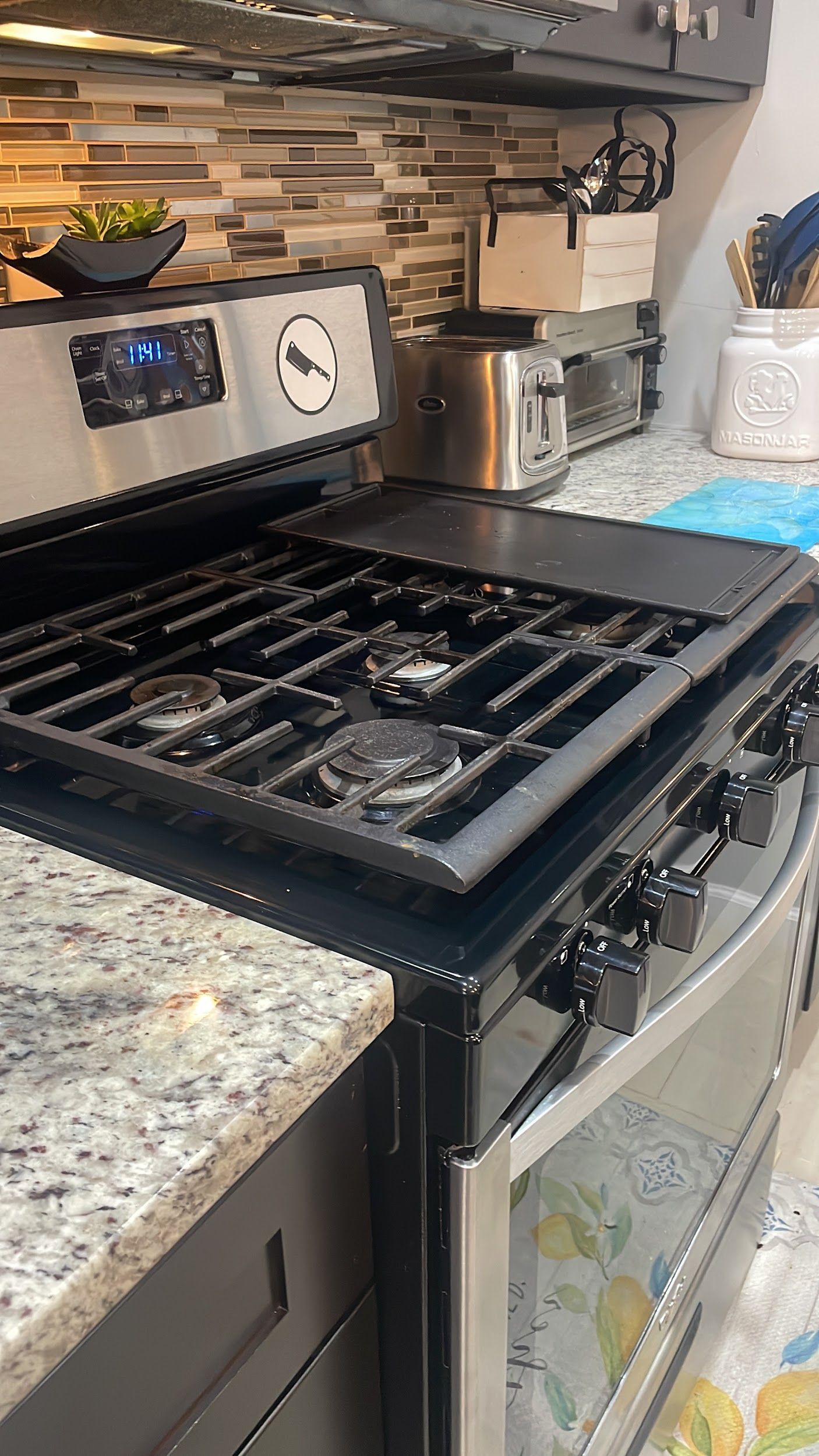 A stove top oven is sitting on top of a granite counter in a kitchen.