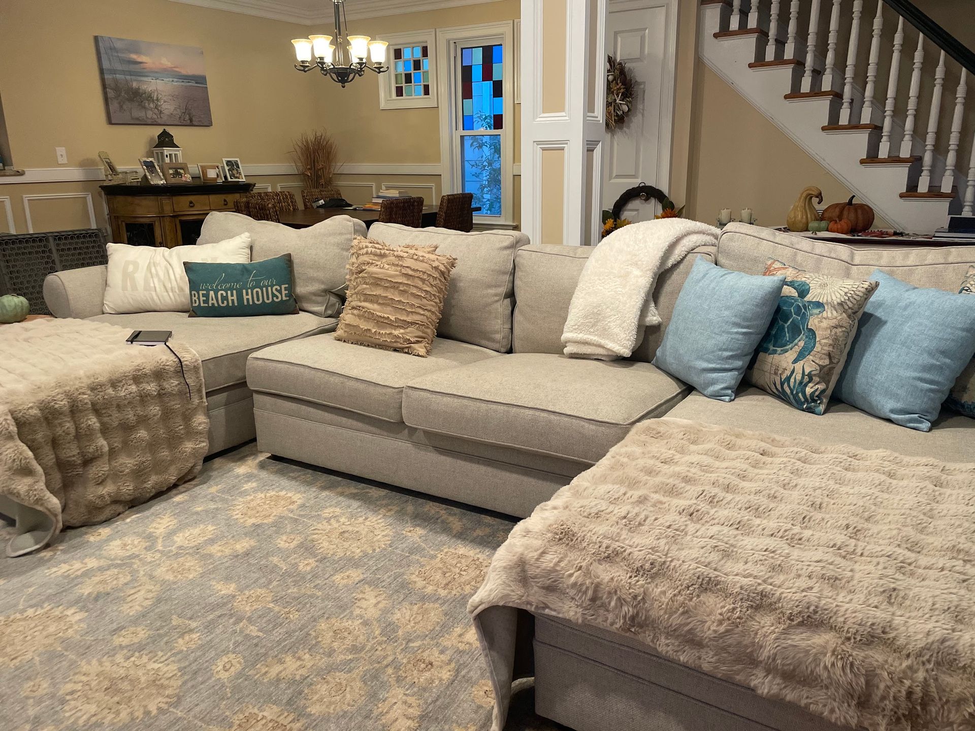 A living room with a large sectional couch and stairs.