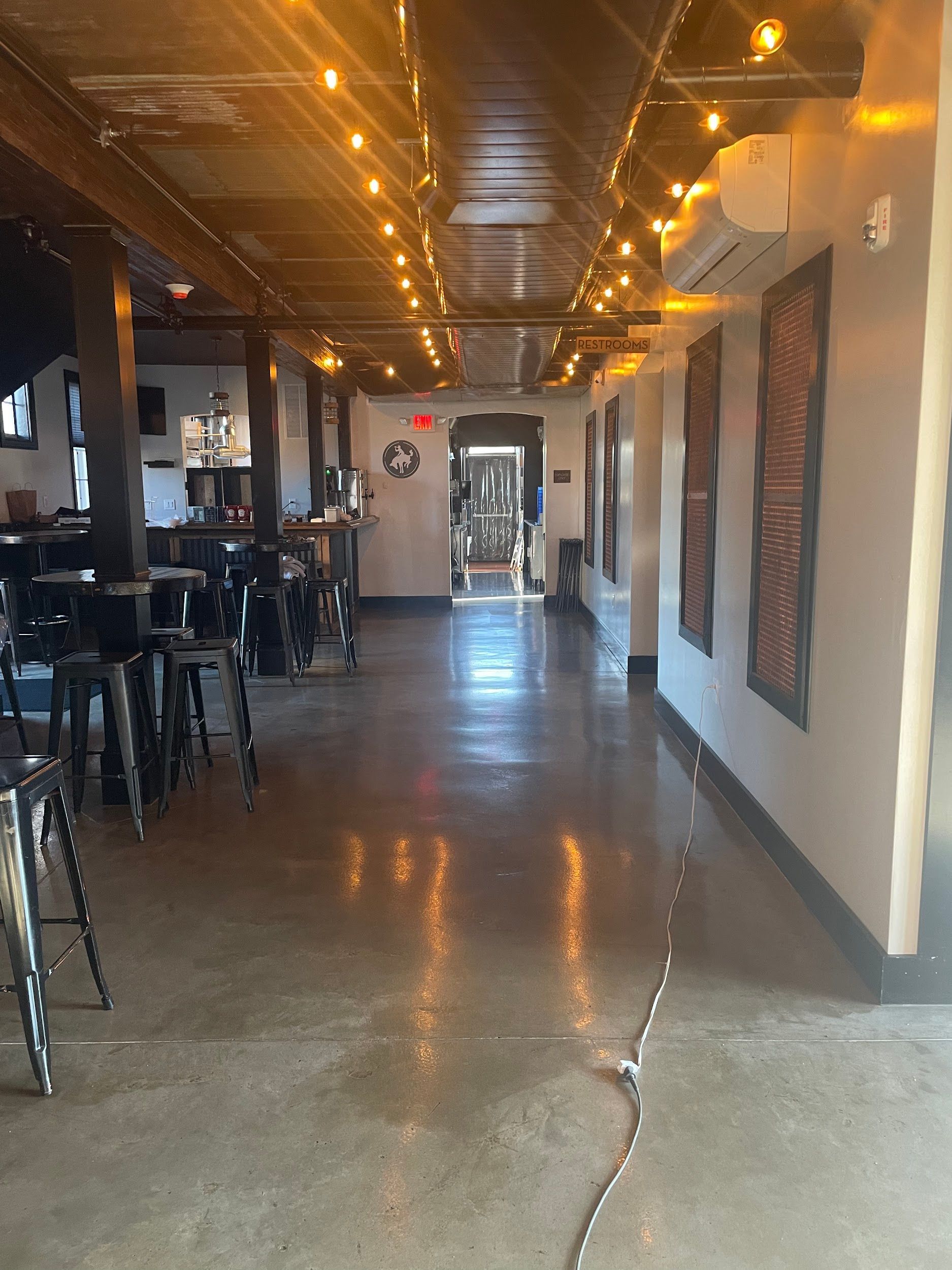 A long hallway in a restaurant with tables and chairs.