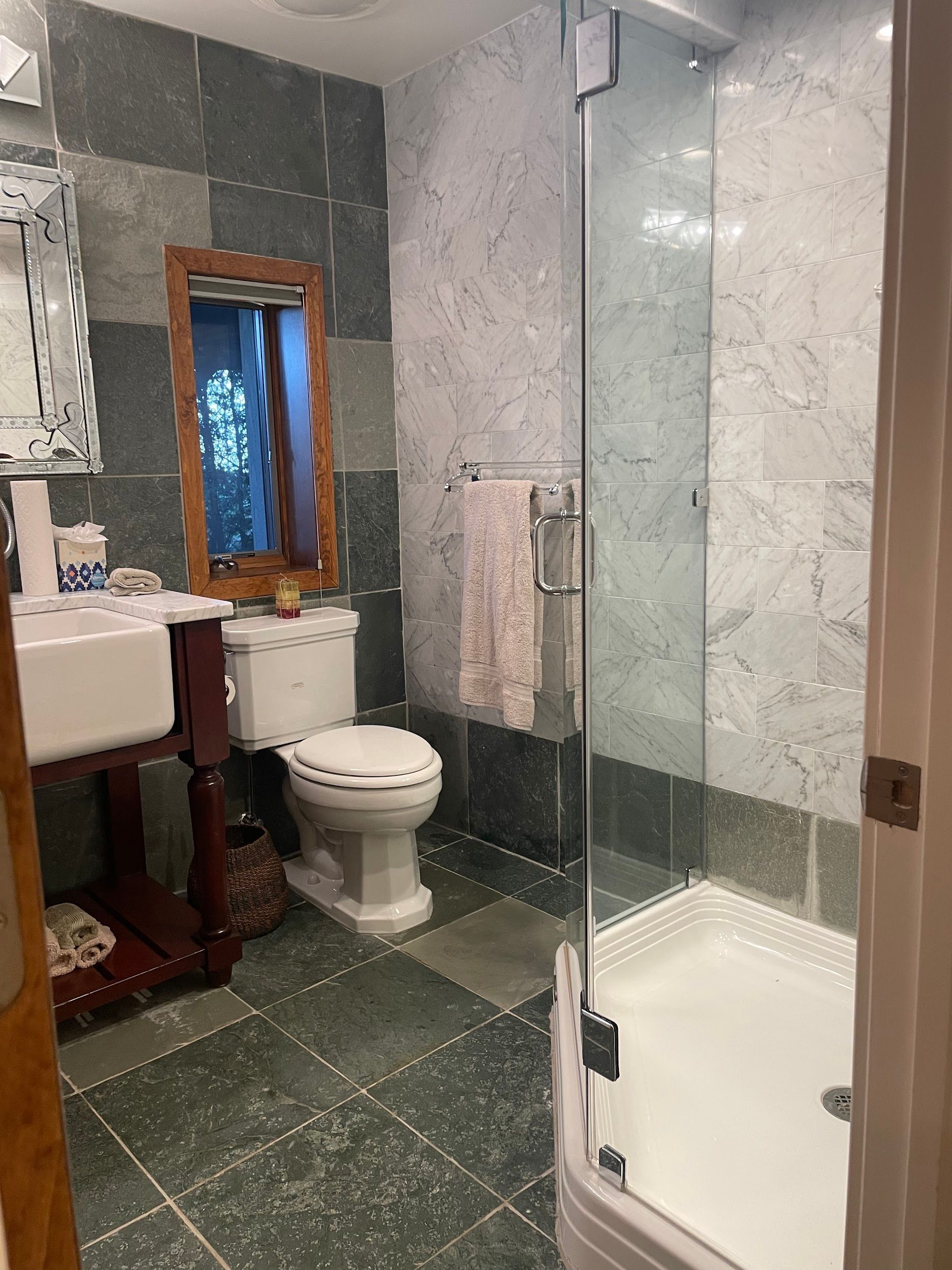 A bathroom with a toilet , sink , mirror and shower.