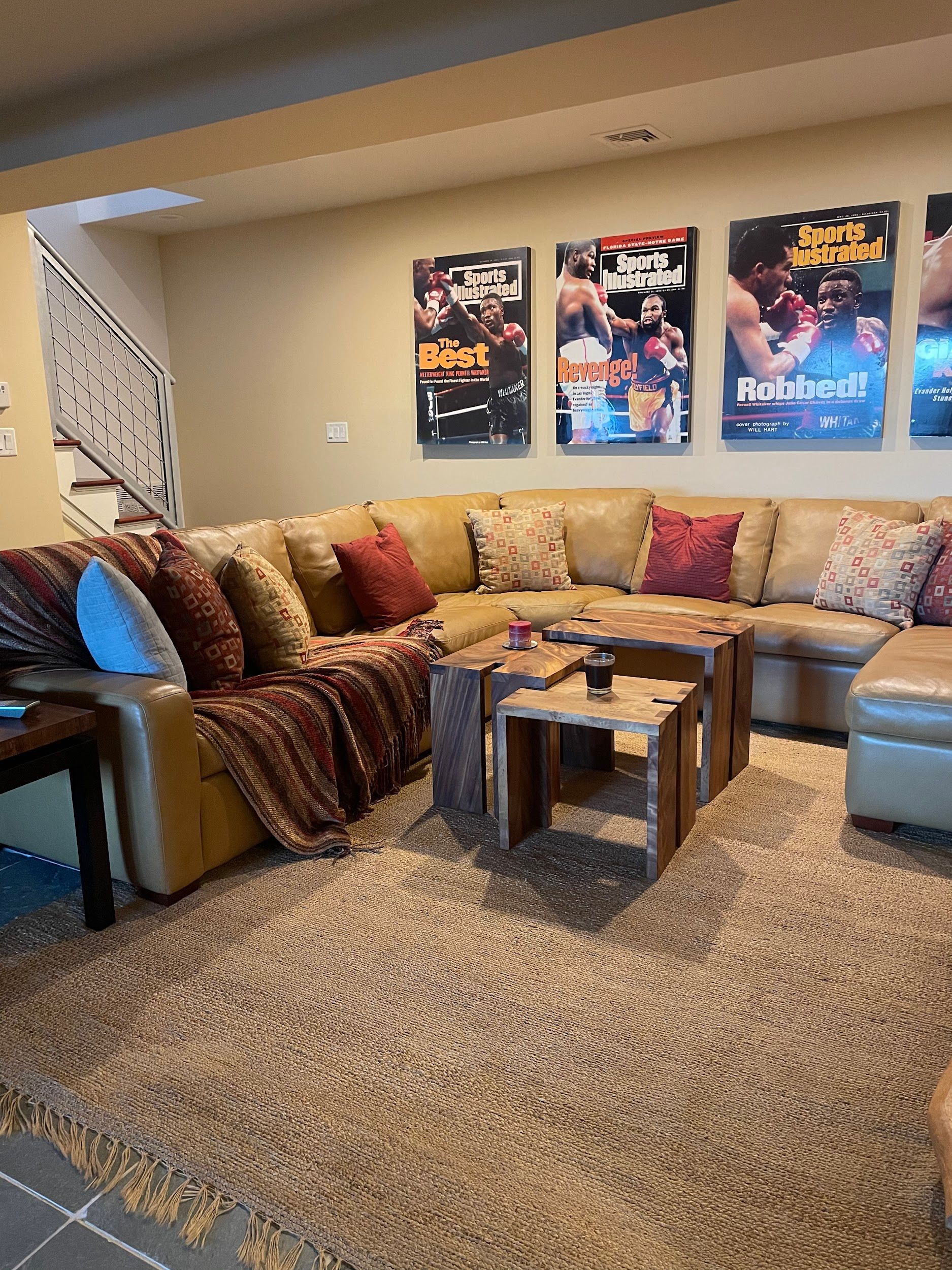 A living room with a couch , coffee table , and boxing posters on the wall.