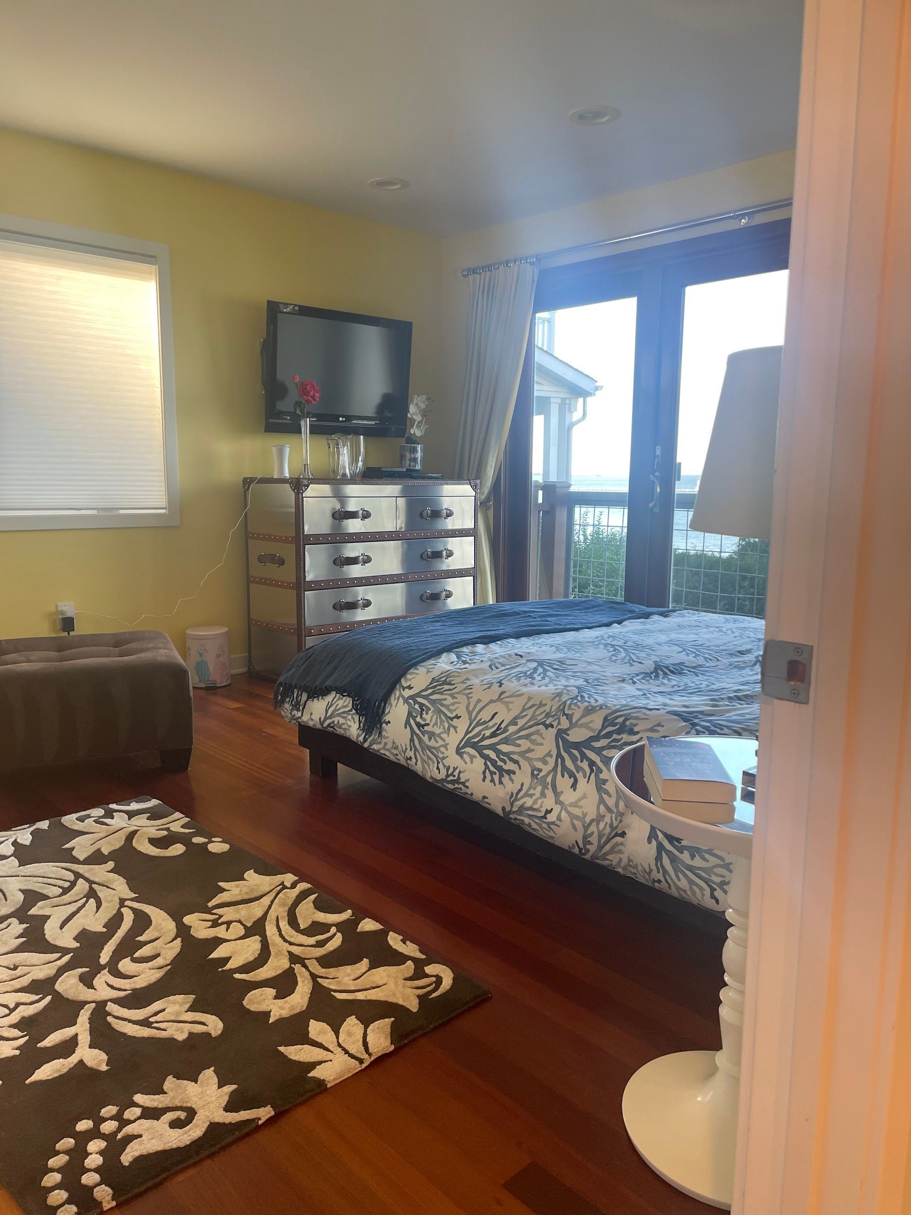 A bedroom with a king size bed , dresser , rug and television.