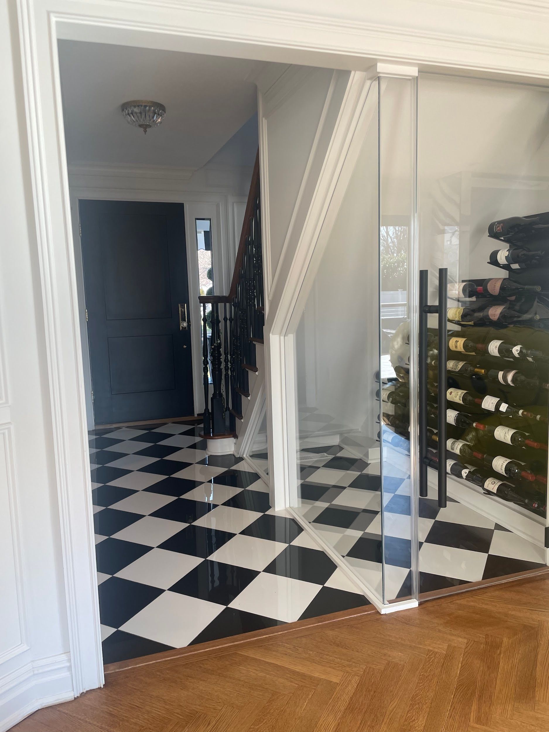 A hallway with a checkered floor and a staircase.