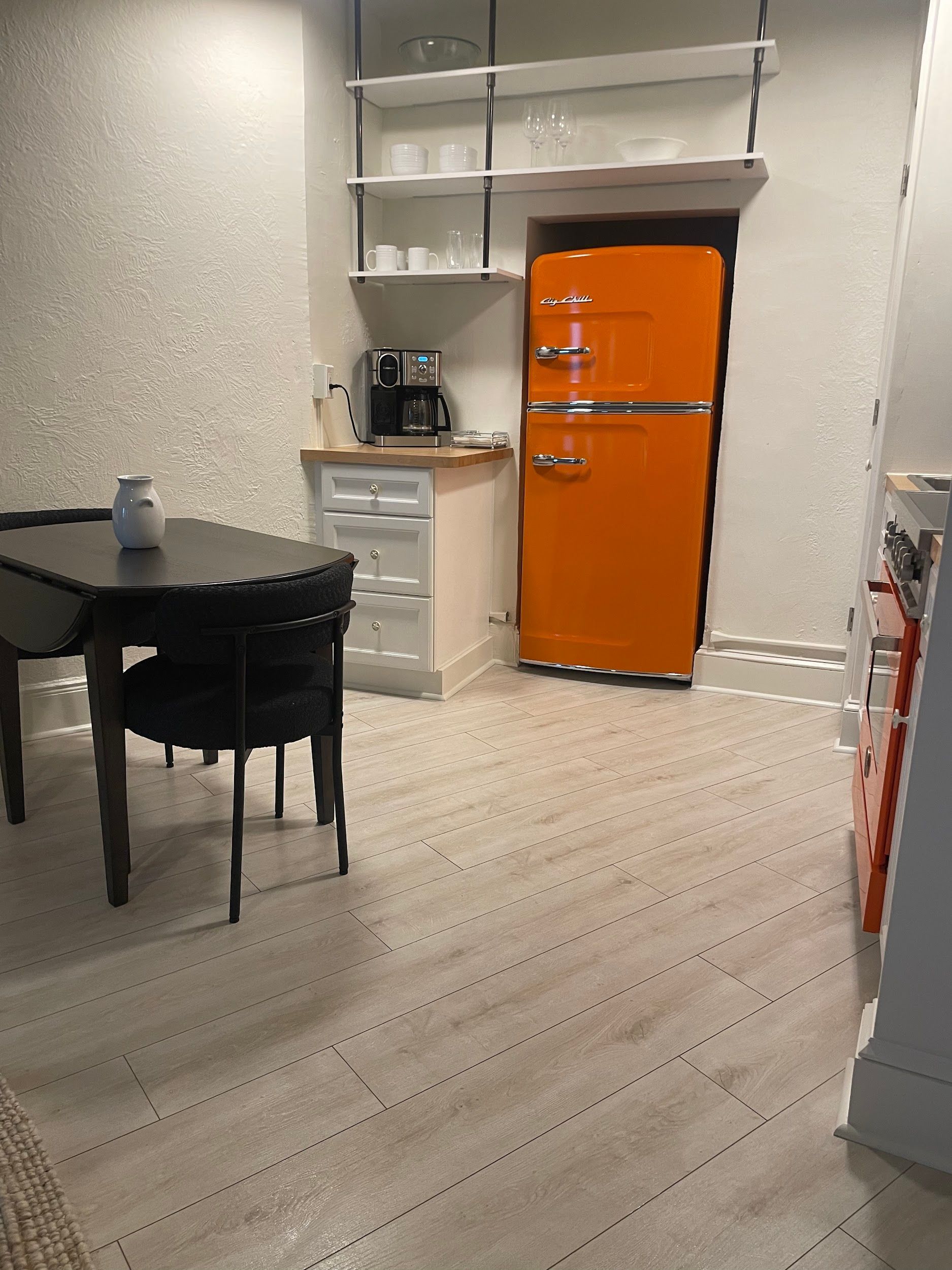 A kitchen with a table and chairs and an orange refrigerator