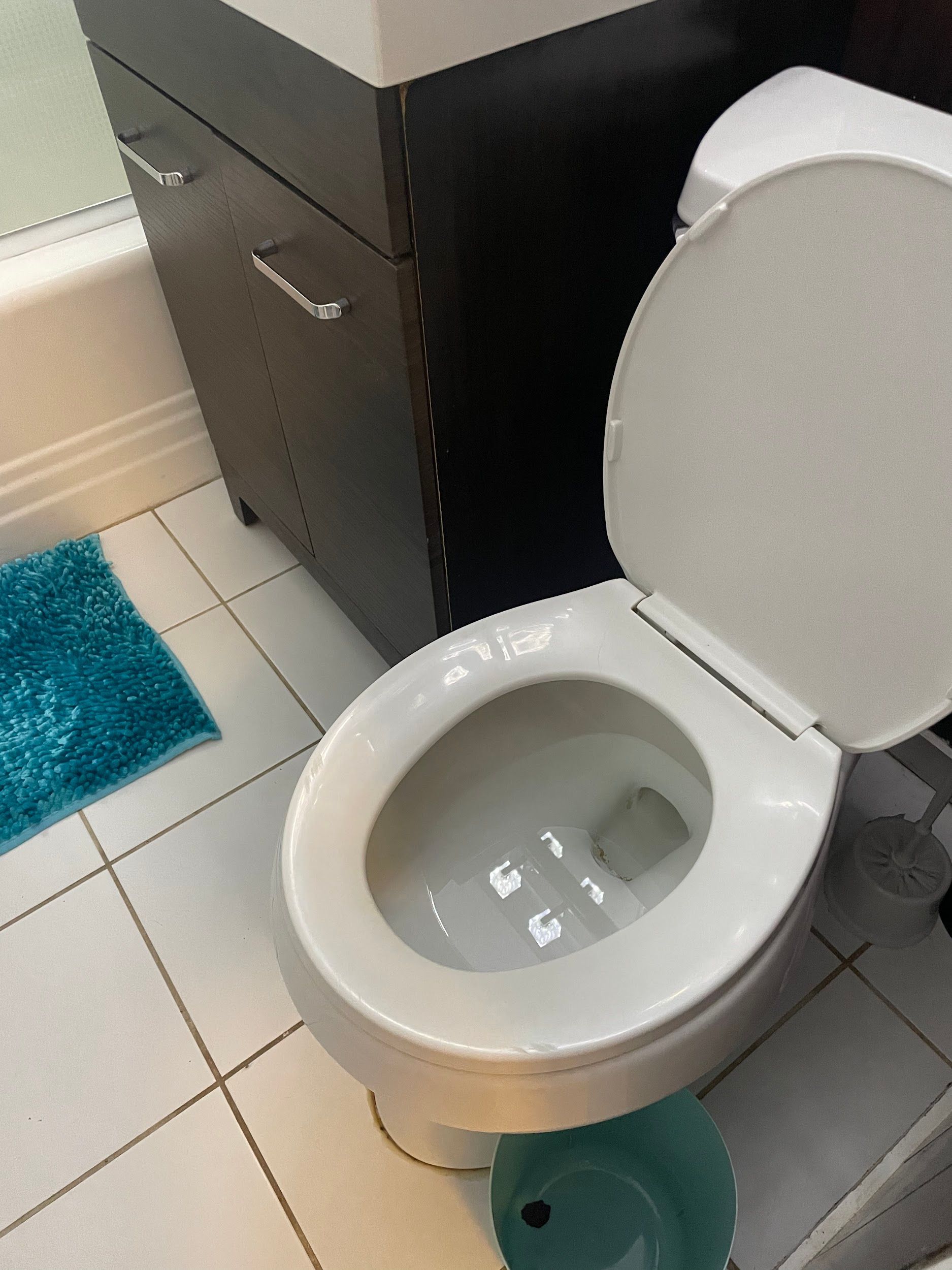 A toilet in a bathroom with the lid up