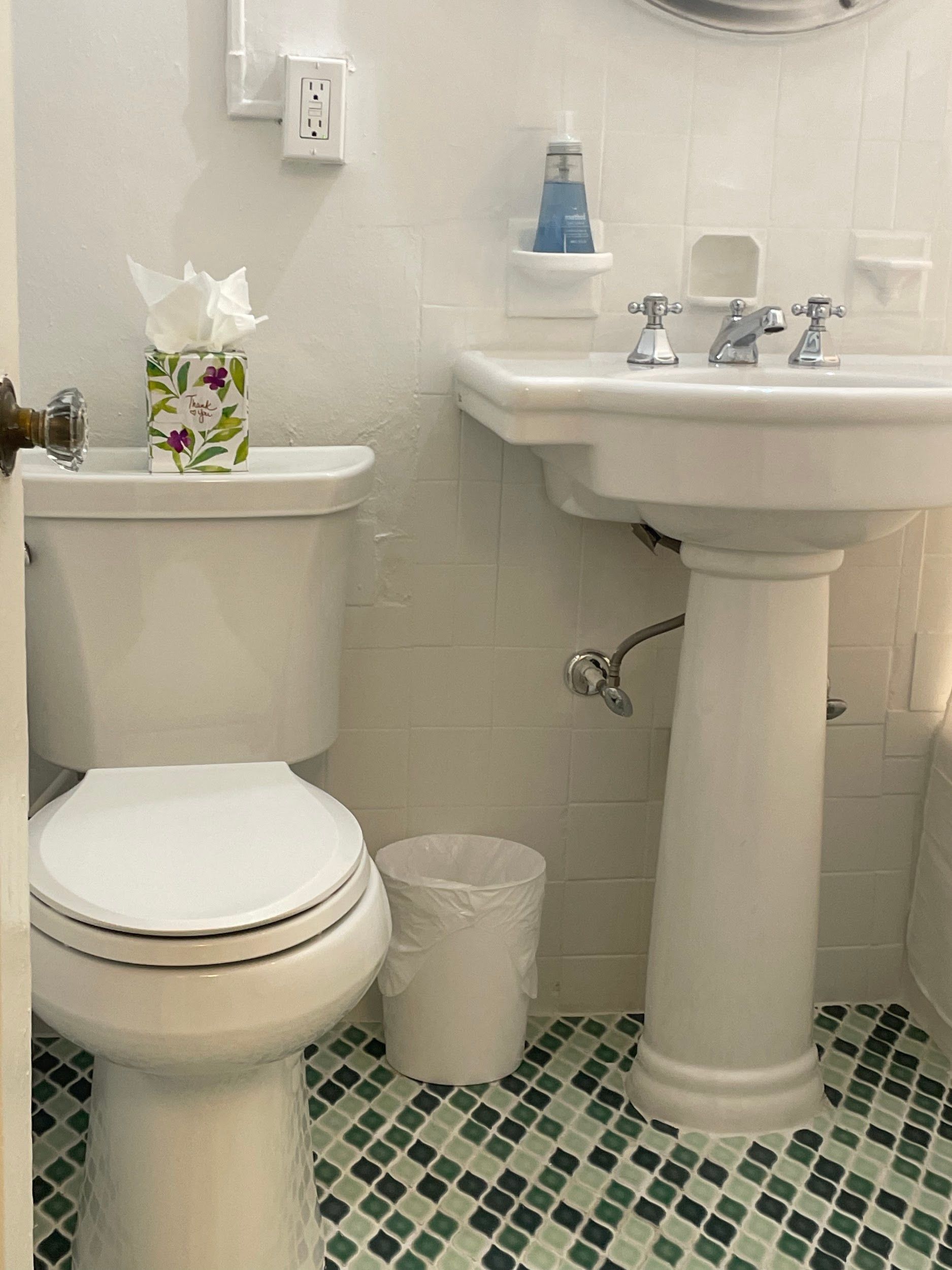 A bathroom with a toilet , sink , and trash can.