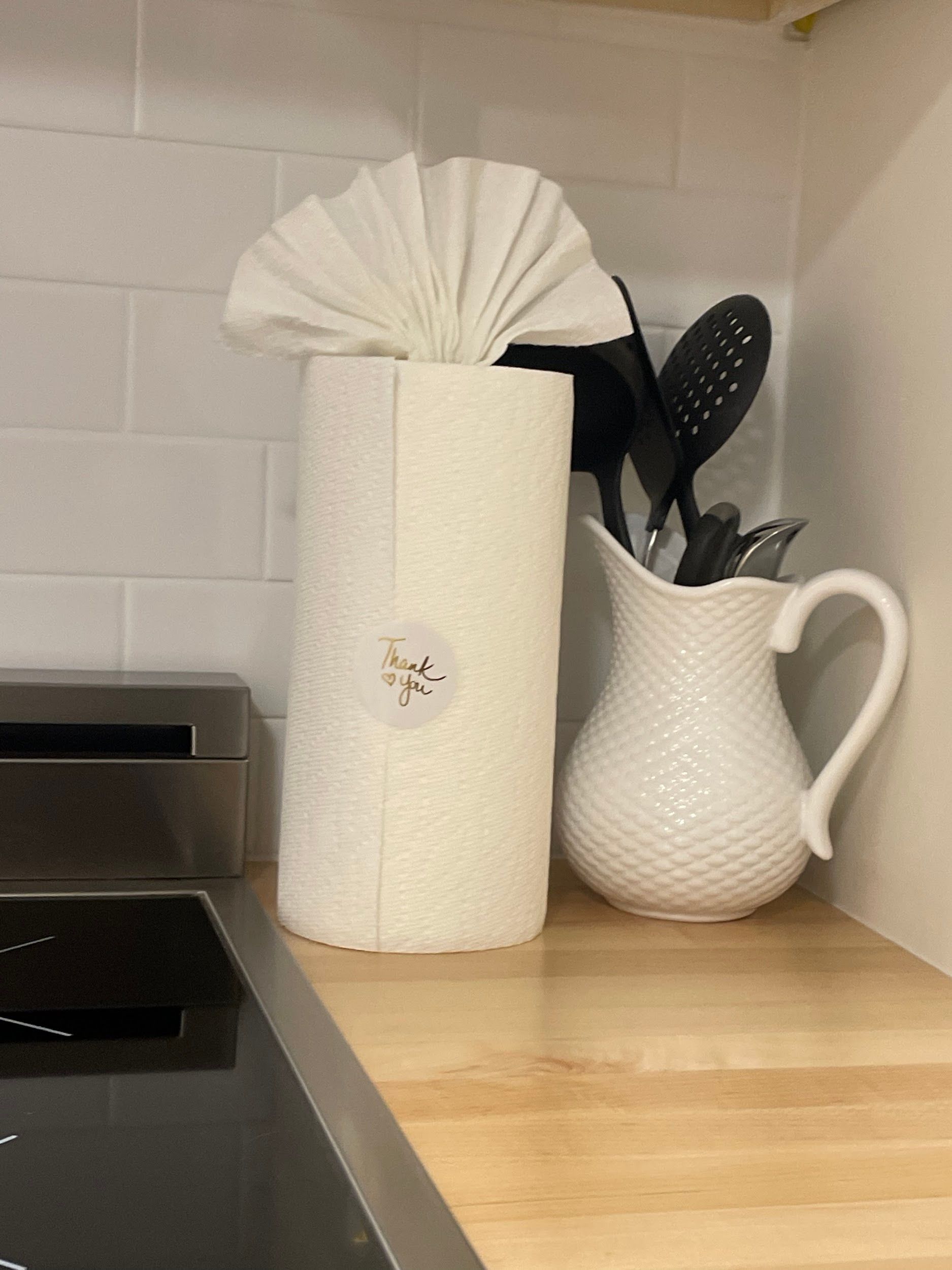 A kitchen counter with a paper towel holder and a pitcher of utensils.