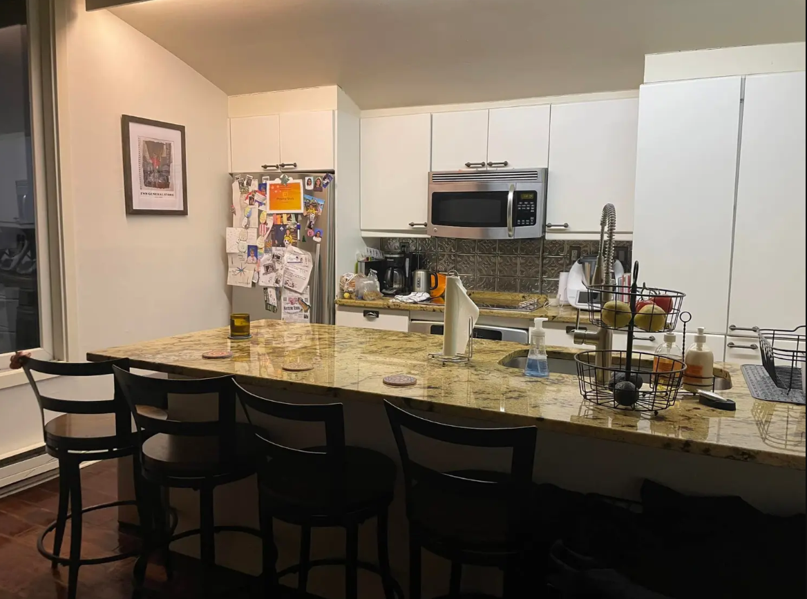A kitchen with a marble counter top and stools