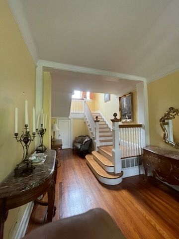 Entryway with wooden floors, stairs, antique furniture, and light yellow walls.