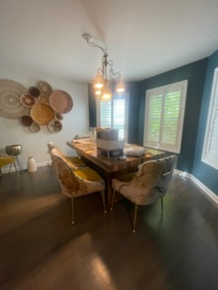 Dining room with a wooden table, velvet chairs, and decorative wall baskets; deep blue wall.