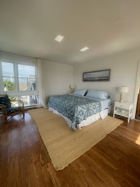 Bedroom with a king bed, neutral rug, white walls, and a view from the window.