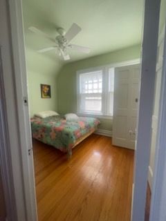Bedroom with a bed, green walls, white door, and hardwood floors.