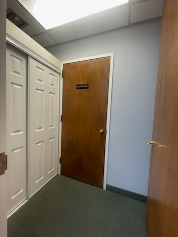 Narrow hallway with closed wooden doors, closet doors on the left and a door on the right.