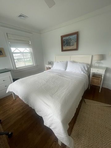 Bedroom with white bedding, nightstands, and a framed painting on the wall.