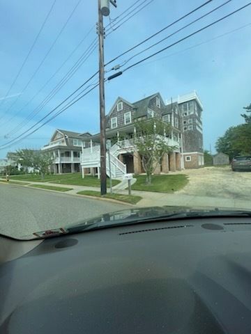 A multi-story gray building with white trim and a curved staircase on a sunny day.