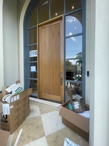 Wooden door with glass panels. Boxes and packages on the porch. House number 