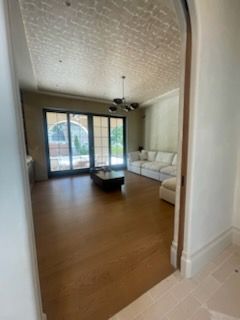 Living room with wooden floors, white couch, and large glass doors leading outside.