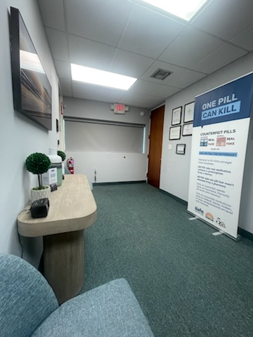 Hallway with green carpet, a desk with decor, and a banner reading 