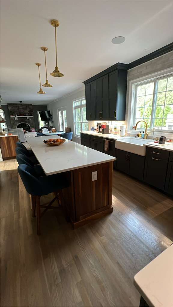 Kitchen with a white countertop island, dark cabinets, and wood floors.